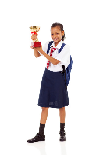 cute primary schoolgirl holding a trophy isolated on white