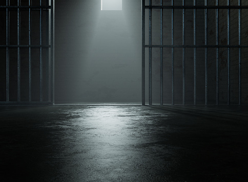 A closeup of a spolight behind jail cells iron bars casting shadows on the concrete prison floor - 3D render