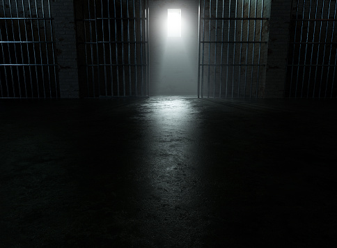 A closeup of a spolight behind jail cells iron bars casting shadows on the concrete prison floor - 3D render