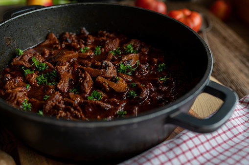 Delicious homemade poultry ragout. Cooked with chopped turkey shank meat, mushrooms and vegetables. Served ready to eat in a pot on rustic and wooden table background. Closeup with selective focus