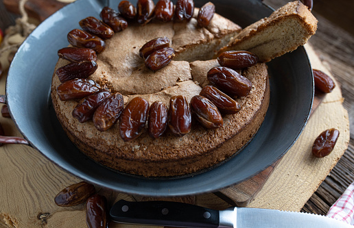 Homemade clean eating cake with hazelnuts and dates. Served whole and ready to eat on rustic and old fashioned table background.