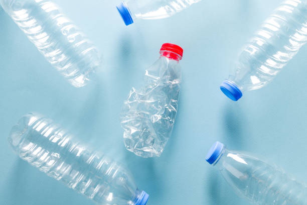 istock Crushed plastic water bottles with blue caps standing around crushed plastic water bottle with red cap on blue background 1665126208