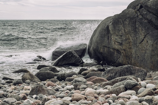 A rocky shoreline and tranquil with the ocean waves crashing against the beach