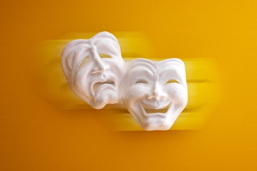 White color theater masks in orange color background