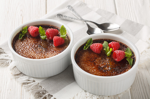 Chocolate creme brulee dessert consisting of a rich custard base topped with a layer of hardened caramelized sugar close-up in a ramekin. Horizontal