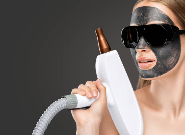 istock A woman with a carbon mask on her face, a beautician does laser carbon peeling on the problem areas of the skin of a young beautiful girl. Cosmetology and professional skin care. 1665138065