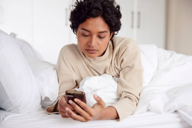 istock Morning Routine: Woman in Bed with Phone 1665142808