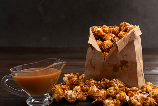 Caramelized popcorn in paper bag on wooden kitchen table
