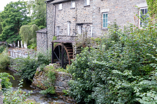 An old English Water mill with its cast iron and wooden wheel at the side of the building