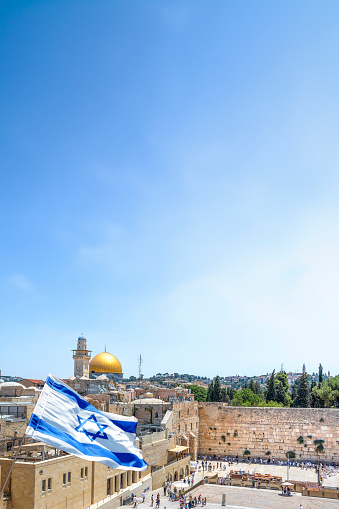 Jerusalem, Israel: An Israeli flag blows in the wind from an elevated view of the Western Wall and the Al-Aqsa Mosque in Jerusalem.