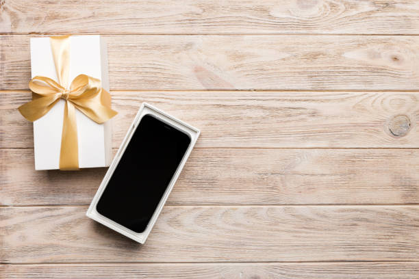 istock Opened gift box with gold ribbon and smartphone on color background, top view. Blank open box packaging mockup , Template for your design - branding mockup 1665180633