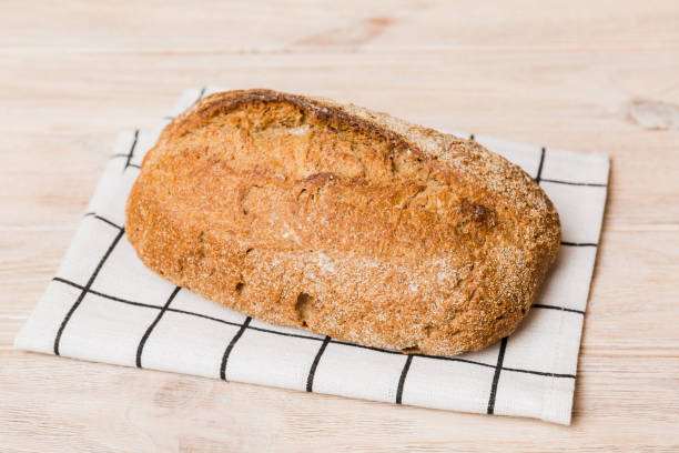 istock freshly baked bread with napkin on rustic table top view. Healthy white bread loaf isolated 1665180652