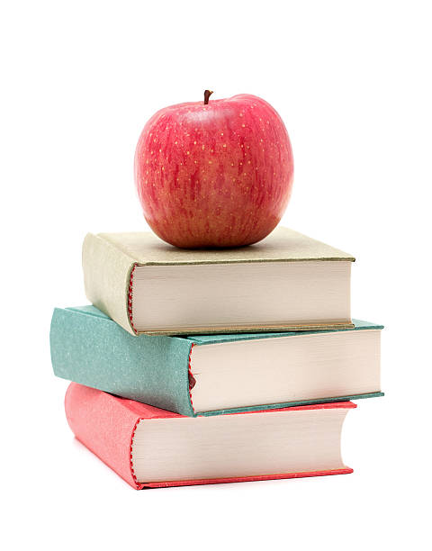 apple on a stack of book - textbook book apple school supplies стоковые фото и изображения