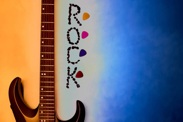 istock Electric guitar neck, rock inscription, picks on an orange blue gradient 1665205986