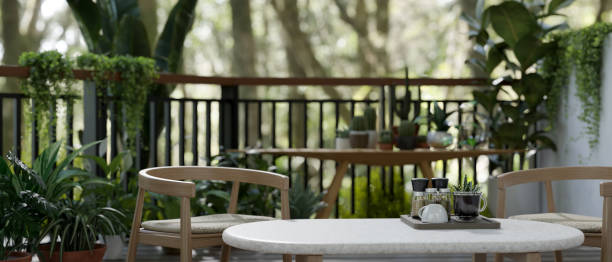 istock Coffee table and armchairs on a green balcony relaxation space with various tropical plants. 1665216576