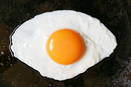 Top view of a sunny side up egg being fried in a pan