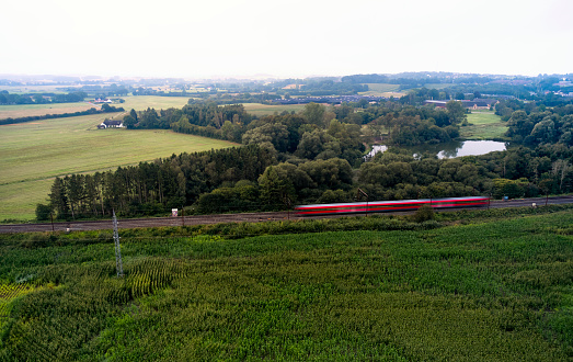 Landscape and traffic. Train crossing rural scene misty morning. Red passenger train in rural landscape