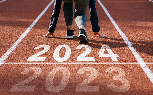 happy new year 2024 symbolizes the start of the new year. Rear view of a man preparing to run on the athletics track engraved with the year 2024. The goal of Success.Getting ready for the new year