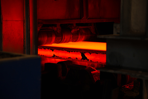 A orange hot steel slab casting on machine in factory.