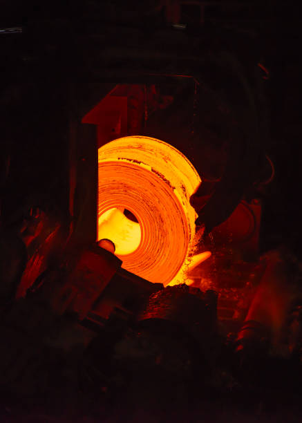A orange hot steel slab passes along a rolling machine at a steel plant.