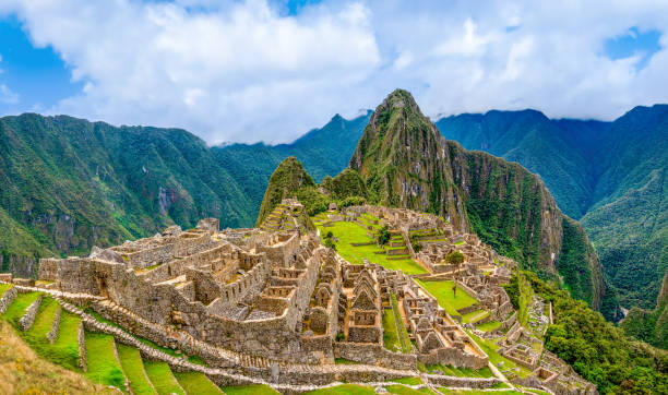 Panoramic View of Machu Picchu, Peru Machu Picchu, Aguas Calientes, Peru: Machu Picchu is a 15th-century Inca citadel located in the Eastern Cordillera of southern Peru on a 2,430-meter (7,970 ft) mountain ridge. It is located in the Machupicchu District within Urubamba Province  above the Sacred Valley, which is 80 kilometers (50 mi) northwest of Cusco. The Urubamba River flows past it, cutting through the Cordillera and creating a canyon with a tropical mountain climate.

Most recent archaeologists believe that Machu Picchu was constructed as an estate for the Inca emperor Pachacuti (1438–1472). Often referred to as the "Lost City of the Incas", it is the most familiar icon of Inca civilization. The Incas built the estate around 1450 but abandoned it a century later, at the time of the Spanish conquest. urubamba province stock pictures, royalty-free photos & images