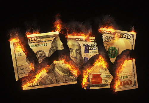 US hundred-dollar bill torn into pieces and set on fire. This image could represent a wide range of economic problems or recklessness. The pieces intentionally do not exactly match up with each other, so they cannot be reconstructed for criminal purposes.