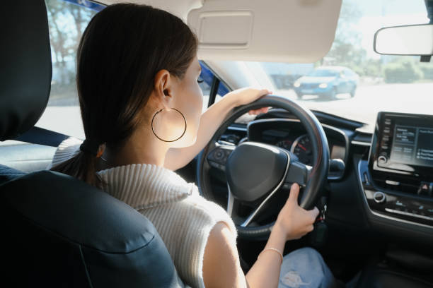 istock Young asian woman drives a car. Back view 1665335086