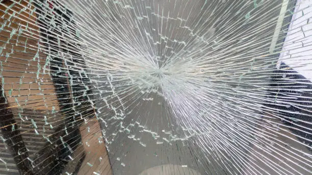 impact on the broken window glass on the commercial facade of a store by attempted theft or street demonstration