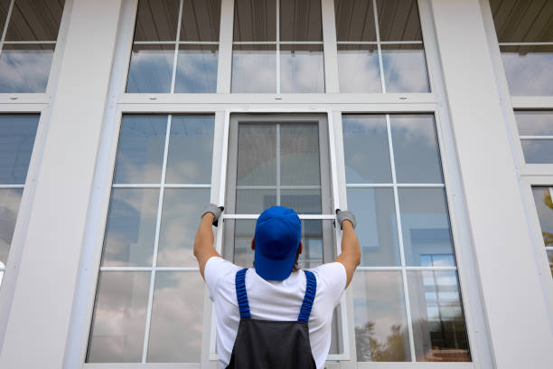Worker in overalls and blue cap, installing mosquito net large plastic window