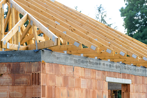 Roof framework of new brick house. Exterior of private property. Architecture industry, concepts of investment in building. Element of unfinished home with board component. Part of construction site