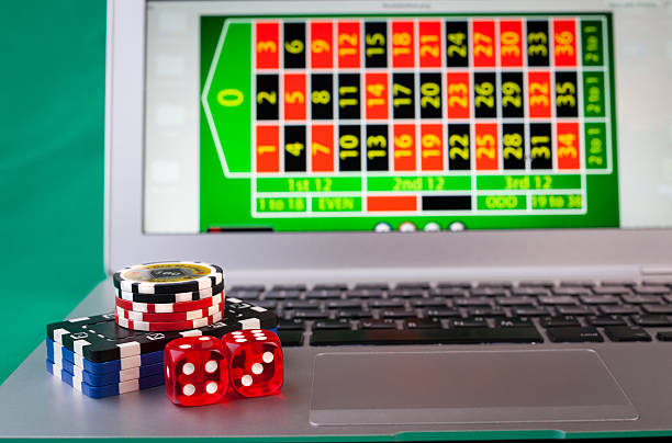 Laptop and Dice Dice and casino chips on silver color laptop conputer number one sports betting site stock pictures, royalty-free photos & images