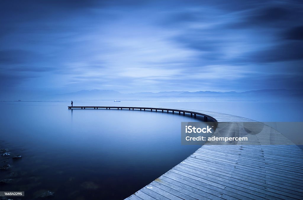 Curve of the Jetty and Man Man Standing on the Curve of the Jetty. Blue Stock Photo