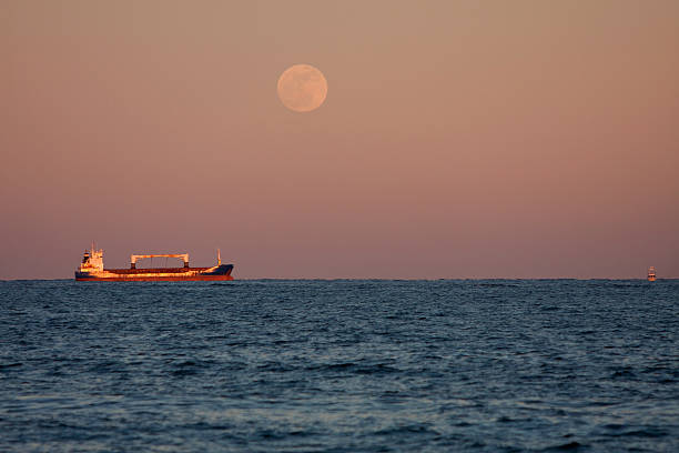 istock Full Moon Shines On Anchored Cargo Ship 166542500