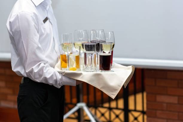 Waiter holding a tray with juice and wine glasses for an event A waiter holding a tray with juice and wine glasses for an event honorably stock pictures, royalty-free photos & images