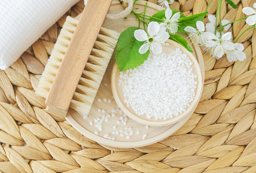 Epsom bath salt and wooden massage foot brush with natural bristles. Eco friendly toiletries set. Natural beauty treatment, pedicure, skin care or zero waste concept. Selective focus.
