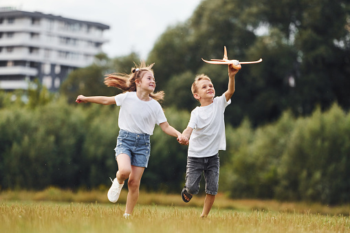 Playful children running with raised arms in sunny day