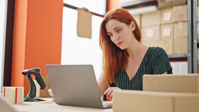 Young redhead woman ecommerce business worker using laptop at office
