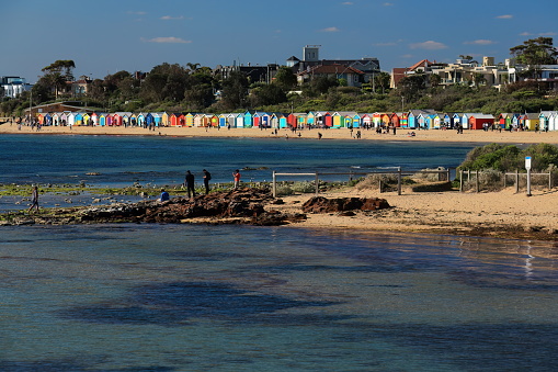 NNE-wards view from Green Point Gardens to 60 of the 82 colorful Victorian bathing boxes along Dendy Street Beach facing west to Port Phillip Bay, Brighton Beach Suburb. Melbourne-VIC-Australia. INCIDENTAL-NON RECOGNIZABLE PEOPLE IN THE IMAGE.