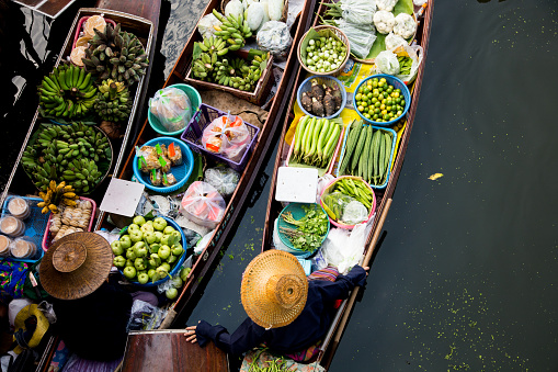 Women selling vegetables and fruit from their canoes at the Tha Kha floating market in Thailand..