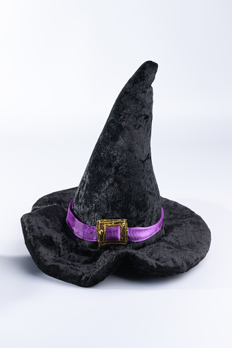 Black, velvet witch's hat with purple and gold accent on a white background.