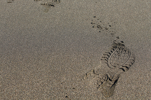 Heavy footprint left on a muddy sand by a male boot.