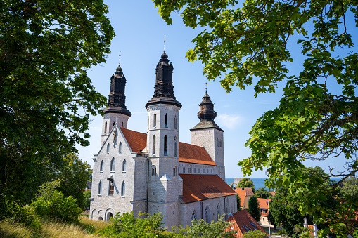 Framed by lush green trees, the Sankta Maria Kathedral in Visby serves as a serene and majestic centerpiece in the landscape. The cathedral's architectural beauty is accentuated by the surrounding foliage, offering a harmonious blend of nature and historical grandeur in the heart of Gotland's medieval city.