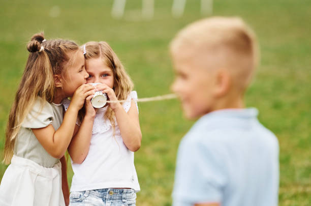 istock Talking, using string can toy. Kids are having fun on the field at daytime together 1665578763
