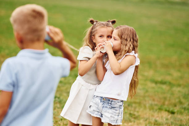 istock Talking, using string can toy. Kids are having fun on the field at daytime together 1665578765