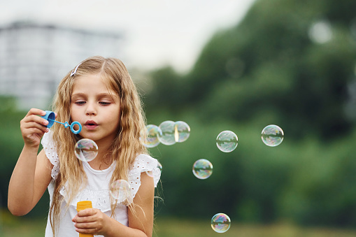 Portrait of little girl that is playing with bubbles outdoors.