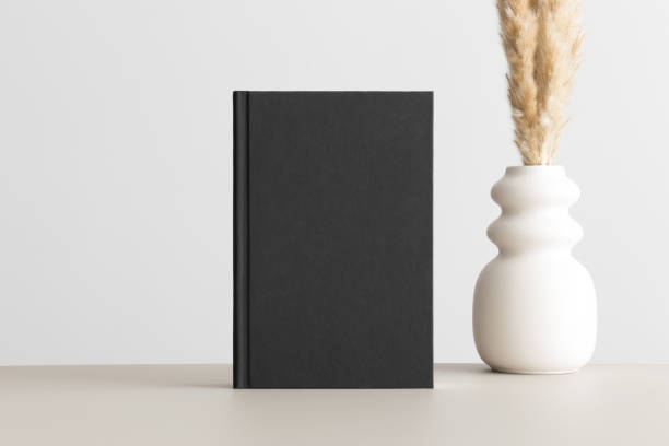 istock Black book mockup with a pampas decoration on the beige table. 1665589344
