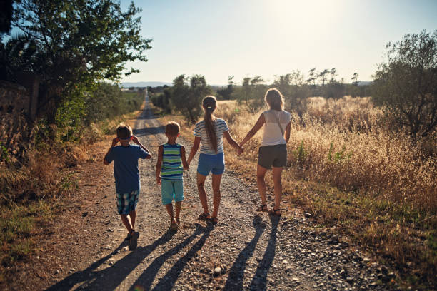 istock Mother with three kids walking on country road 1665592102
