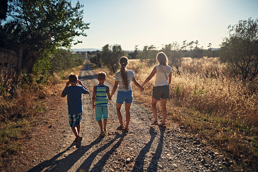 Mother and three kids are walking on a country road in Tuscany\nShot with Nikon D810