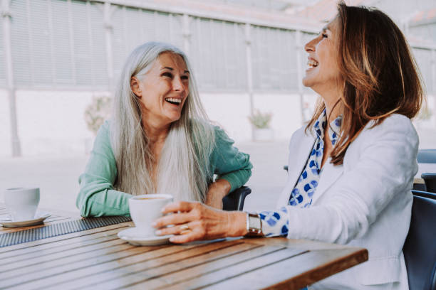 Beautiful senior women meeting outdoors in the city Beautiful senior women bonding outdoors in the city - Attractive cheerful mature female friends having fun, shopping and bonding, concepts about elderly lifestyle female-friendship stock pictures, royalty-free photos & images