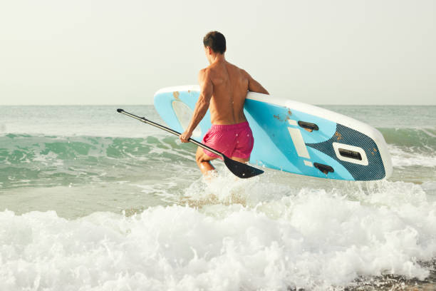 istock Paddle-board entering the water with the board on hand. 1665614996